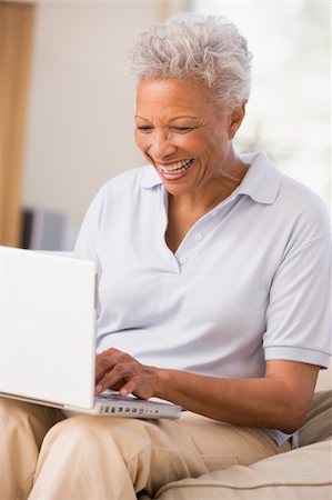 Woman in living room with laptop smiling Stock Photo - Budget Royalty-Free & Subscription, Code: 400-05000470