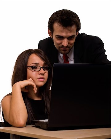 Attractive brunette woman sitting on a desk in front of laptop computer with a man coworker standing behind her both looking at screen Stock Photo - Budget Royalty-Free & Subscription, Code: 400-05002782