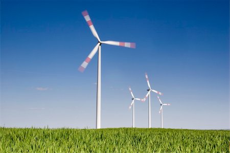 Rotating wind-turbines with green grass in the foreground against blue sky. Motion blurred propellers. Foto de stock - Super Valor sin royalties y Suscripción, Código: 400-05017225