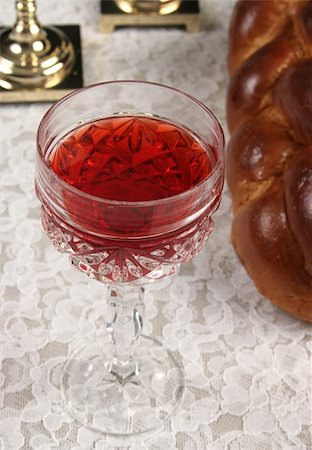A closeup photo of a glass of wine for Shabbat with challah bread and candlesticks in the background. Foto de stock - Super Valor sin royalties y Suscripción, Código: 400-05019533