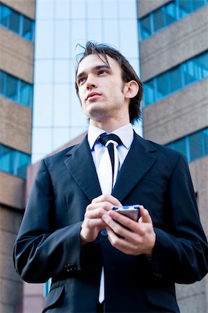 young handsome businessman (corporate executive) is using his palmtop (PDA) Photographie de stock - Aubaine LD & Abonnement, Code: 400-05010136