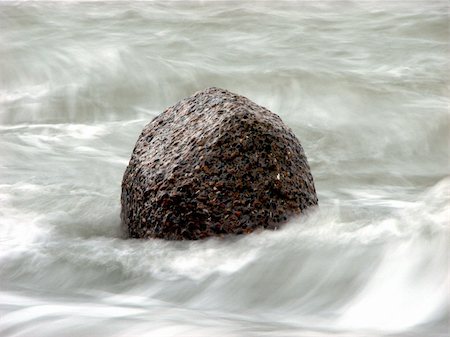 A rock poking out of the water with waves crashing all around. Long shutter speed. Stockbilder - Microstock & Abonnement, Bildnummer: 400-05026240