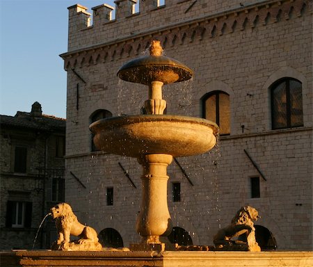An old Italian fountain in the main town square of Assissi. Droplets of water from the fountain are highlighted in the warm golden glow of the evening just before sunset. Stock Photo - Budget Royalty-Free & Subscription, Code: 400-05028396
