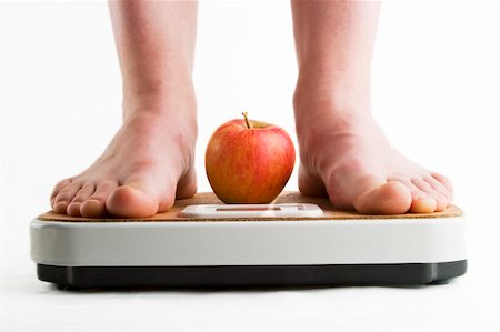 A pair of female legs standing on a bathroom scale with an apple between them. Stock Photo - Budget Royalty-Free & Subscription, Code: 400-05029050