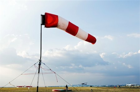 A red and white windsock flying in the wind to signal direction on an airfield Fotografie stock - Microstock e Abbonamento, Codice: 400-05021223