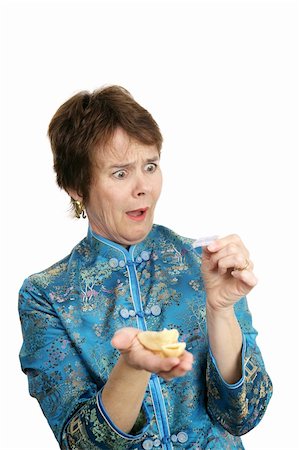 A woman dressed in a chinese blouse is shocked by the fortune inside her cookie.  Isolated on white. Stock Photo - Budget Royalty-Free & Subscription, Code: 400-05022180