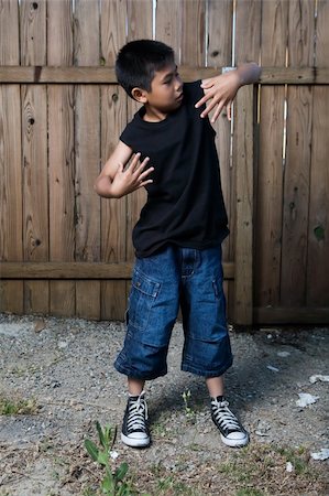 simsearch:400-03994929,k - Young asian boy standing outside beside a tall wooden fence wearing jeans and black tshirt Stockbilder - Microstock & Abonnement, Bildnummer: 400-05035477