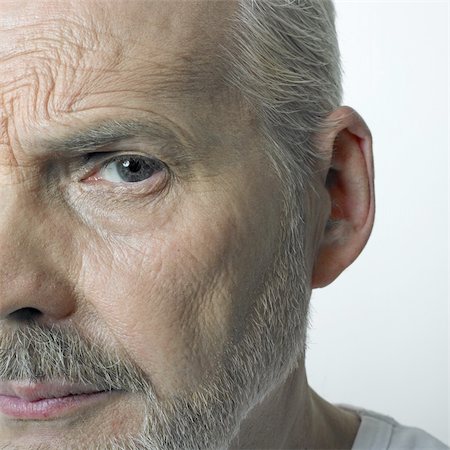 Studio half face portrait of a matured caucasian man with grey beard, wrinkled skin and serious facial expression. Stock Photo - Budget Royalty-Free & Subscription, Code: 400-05036195