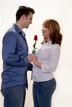 Man and woman facing and looking at each other with man offering the woman a red rose standing on white Photographie de stock - Aubaine LD & Abonnement, Code: 400-05036827