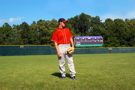 simsearch:400-04495626,k - young teen male stands on baseball field in red navy uniform.  He is looking sideways.  Scoreboard is in background of picture. Fotografie stock - Microstock e Abbonamento, Codice: 400-05030617