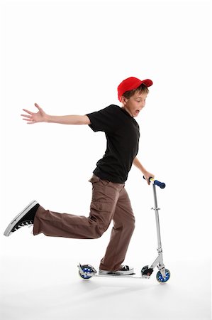 An active happy child riding and playing on a scooter on a white background Stock Photo - Budget Royalty-Free & Subscription, Code: 400-05033037