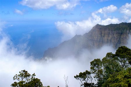 Beautiful Na Pali Coast is hugged by a large white cloud.  Vivid blue sky and water below. Photographie de stock - Aubaine LD & Abonnement, Code: 400-05033945