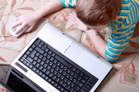 sergeitelegin (artist) - The little boy laying on a sofa works on a laptop Stock Photo - Budget Royalty-Free & Subscription, Code: 400-05046560