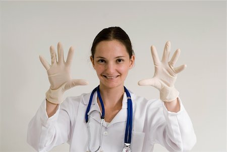 Young female doctor holding her gloved hands out and smiling playfully Stock Photo - Budget Royalty-Free & Subscription, Code: 400-05057401