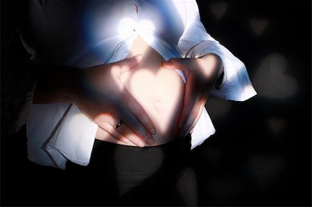 simsearch:400-07557771,k - Pregnancy - woman belly with lights of hearts Photographie de stock - Aubaine LD & Abonnement, Code: 400-05050538