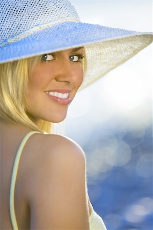 simsearch:400-04058311,k - Portrait of a stunningly beautiful young blond woman sitting on the beach wearing a hat and bathed in sunshine while the sun glistens off the sea behind her Foto de stock - Super Valor sin royalties y Suscripción, Código: 400-05051720