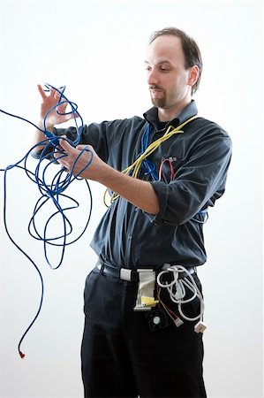 Computer technician looking confuse trying to untie network cable Stock Photo - Budget Royalty-Free & Subscription, Code: 400-05052340