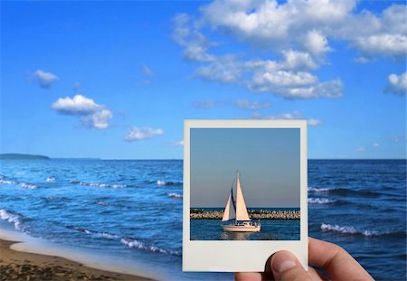 finger lakes - hand holding a holiday photo, beautiful seashore in background, photo inside is my property Stock Photo - Budget Royalty-Free & Subscription, Code: 400-05053057