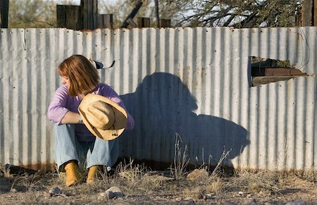 Woman in a Cowboy hat sitting against a Corrugated Metal fence and Looking to her Right. Stock Photo - Budget Royalty-Free & Subscription, Code: 400-05053758