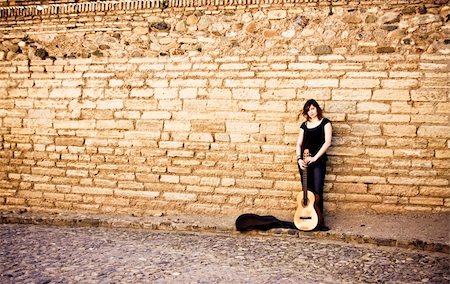 photographic portraits poor people - Street artist standing with her guitar on the wall Stock Photo - Budget Royalty-Free & Subscription, Code: 400-05064589