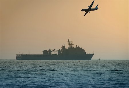plane silhouette side - Airplane flying over warship in early morning Stock Photo - Budget Royalty-Free & Subscription, Code: 400-05065997
