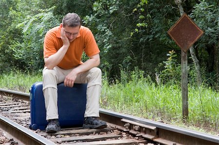 suitcase railway track - Tired man sitting on his suitcase on a railway Stock Photo - Budget Royalty-Free & Subscription, Code: 400-05066576