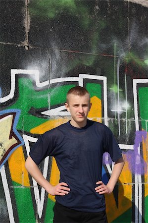 Teenage boy in dark blue t-shirt standing against wall painted with graffiti Stock Photo - Budget Royalty-Free & Subscription, Code: 400-05068031