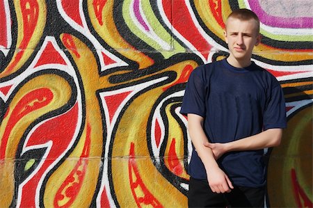 Teenage boy in dark blue t-shirt standing against wall painted with graffiti Stock Photo - Budget Royalty-Free & Subscription, Code: 400-05068032