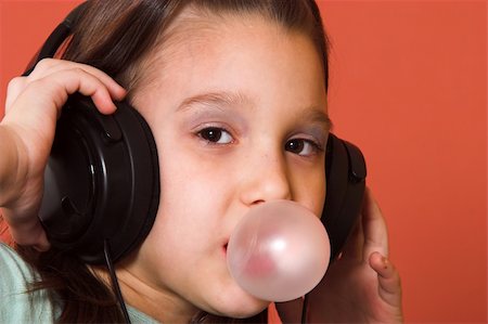 Young girl listening to music and making a bubble from chewing gum Stock Photo - Budget Royalty-Free & Subscription, Code: 400-05068061