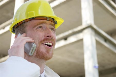 Man with helmet talking on a cell phone in front of a building construction Stock Photo - Budget Royalty-Free & Subscription, Code: 400-05068337