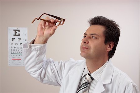 eye doctor (male) - An eye doctor optometrist inspects a pair of eyeglasses, Stock Photo - Budget Royalty-Free & Subscription, Code: 400-05068711
