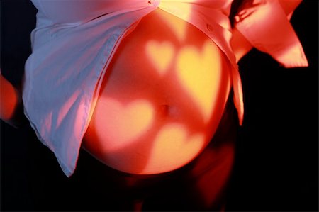 simsearch:400-07557771,k - Pregnancy - woman belly with lights of hearts Photographie de stock - Aubaine LD & Abonnement, Code: 400-05062073