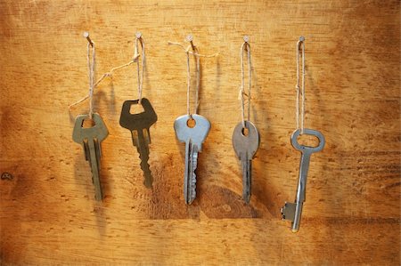 Various keys dangle on a rope with nails on wooden background Stock Photo - Budget Royalty-Free & Subscription, Code: 400-05071554
