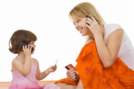 A young woman talking on the phone and holding in her hand a banking card and the little girl imitate her Stock Photo - Budget Royalty-Free & Subscription, Code: 400-05084735