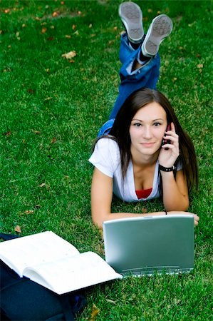 Cute teen girl laying down on the grass studying with her laptop Stock Photo - Budget Royalty-Free & Subscription, Code: 400-05084743
