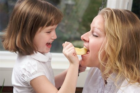 Daughter Having Fun Feeding Mom an Apple Slice Stock Photo - Budget Royalty-Free & Subscription, Code: 400-05086669