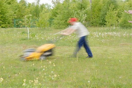 A long exposure shot. Teenboy mowing lawn with a grass mower on a spring day. Stock Photo - Budget Royalty-Free & Subscription, Code: 400-05080403
