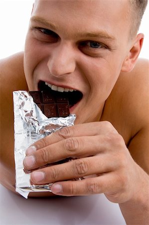 physical fit food - smiling muscular male eating chocolate on an isolated background Stock Photo - Budget Royalty-Free & Subscription, Code: 400-05082994