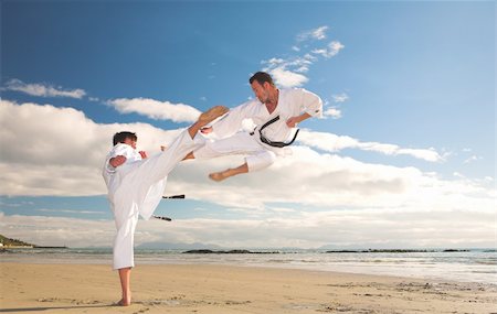 play fight - Young adult men practicing Karate on the beach. One is in a high kick and the other flying through the air (some movement on the edges) Foto de stock - Super Valor sin royalties y Suscripción, Código: 400-05083181