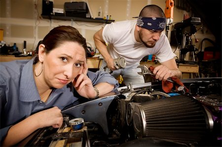 Bored woman leaning on car with male mechanic ignoring her in background Stock Photo - Budget Royalty-Free & Subscription, Code: 400-05097963