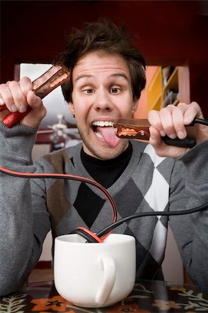 electricity humor - Young man holding jumper cables coming out of coffee mug Stock Photo - Budget Royalty-Free & Subscription, Code: 400-05090527