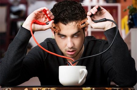 simsearch:400-04554624,k - Young man holding jumper cables coming out of coffee mug Stock Photo - Budget Royalty-Free & Subscription, Code: 400-05090528