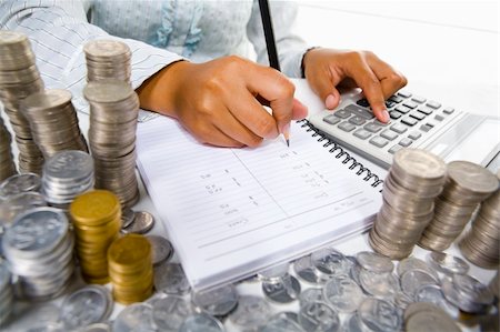 Horizontal view of a woman's body part (unrecognizable) working on book keeping and using calculator with lots of coins around her. Mostly, Indonesian coins showed clearly here. Stock Photo - Budget Royalty-Free & Subscription, Code: 400-05091189