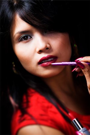 A young woman using a lipstick brush. Very shallow depth of field, high contrast. Foto de stock - Super Valor sin royalties y Suscripción, Código: 400-05091218