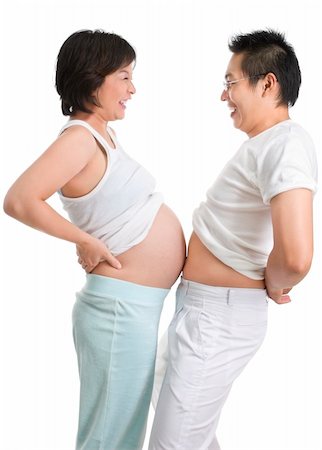 Husband and pregnant wife are playing by comparing their stomach size, shot against white background. Foto de stock - Super Valor sin royalties y Suscripción, Código: 400-05091953
