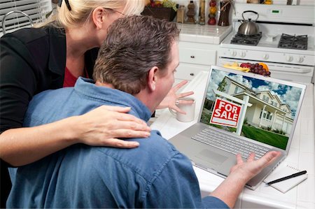simsearch:400-06857713,k - Couple In Kitchen Using Laptop to Research Real Estate. Screen can be easily used for your own message or picture. Picture on screen is my copyright as well. Fotografie stock - Microstock e Abbonamento, Codice: 400-05106445