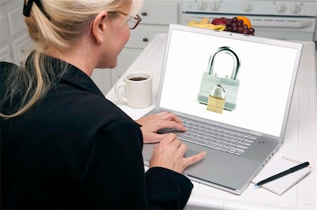 simsearch:400-05129327,k - Woman In Kitchen Using Laptop with High Security Level. Screen can be easily used for your own message or picture. Picture on screen is my copyright as well. Stock Photo - Budget Royalty-Free & Subscription, Code: 400-05106607