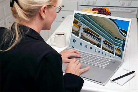 simsearch:400-06857713,k - Woman In Kitchen Using Laptop to Research Travel, Vacation and Cruises. Screen can be easily used for your own message or picture. Picture on screen is my copyright as well. Fotografie stock - Microstock e Abbonamento, Codice: 400-05106602
