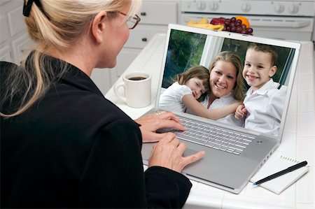 simsearch:400-06857713,k - Woman In Kitchen Using Laptop See Friends and Family. Screen can be easily used for your own message or picture. Picture on screen is my copyright as well. Fotografie stock - Microstock e Abbonamento, Codice: 400-05106603