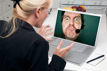 simsearch:400-06857713,k - Shocked Woman In Kitchen Using Laptop with Grumpy Customer Support Man On Screen. Screen can be easily used for your own message or picture. Picture on screen is my copyright as well. Fotografie stock - Microstock e Abbonamento, Codice: 400-05106625
